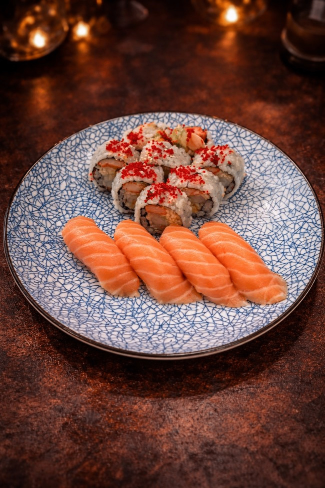 Sushi platter with salmon nigiri and topped rolls on a blue patterned plate