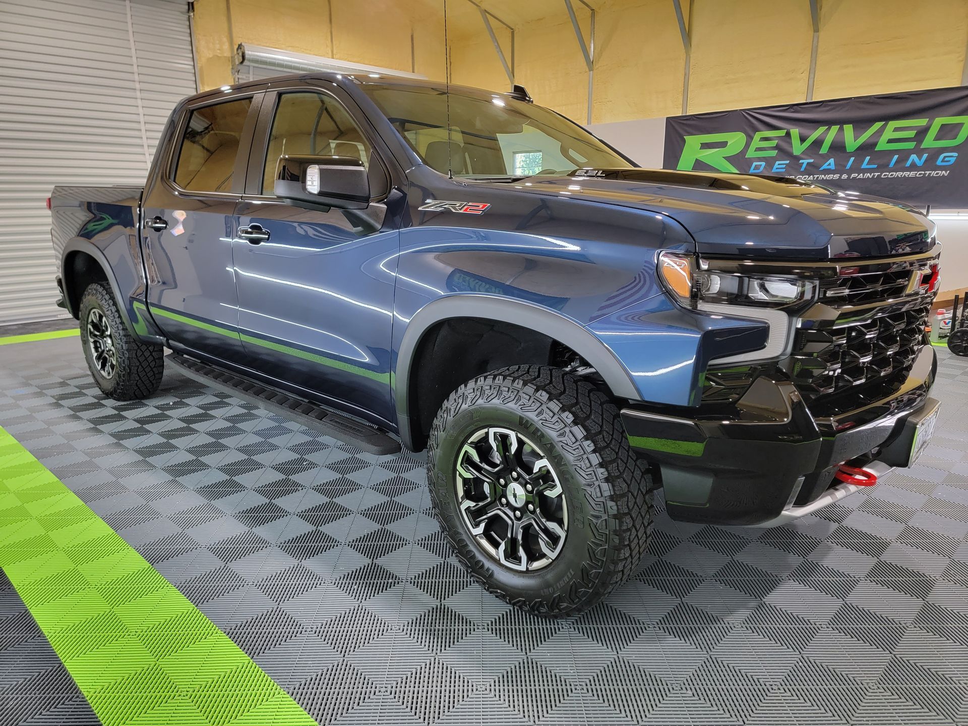 A blue chevrolet silverado pickup truck is parked in a garage.