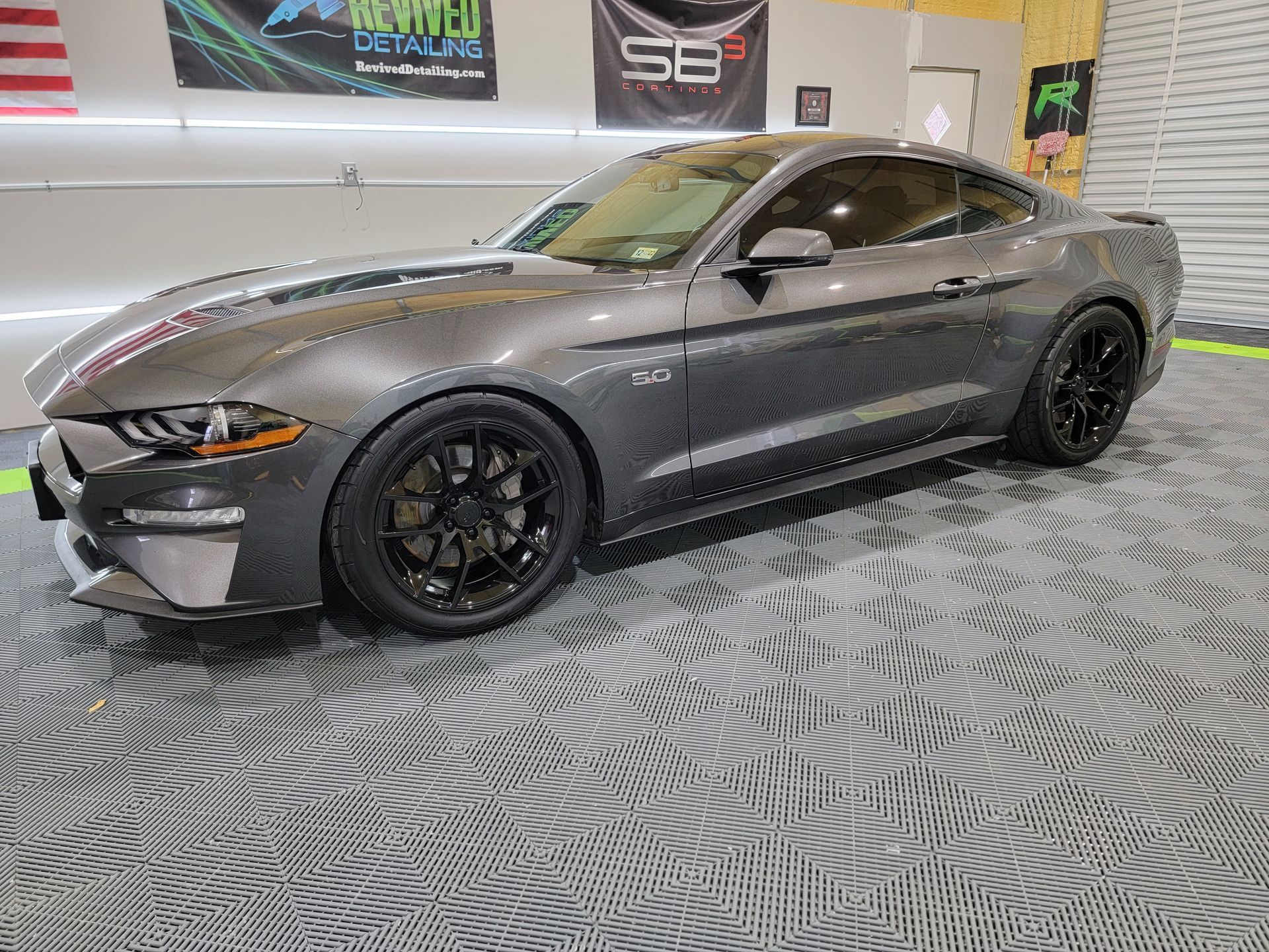 A gray ford mustang is parked in a garage.