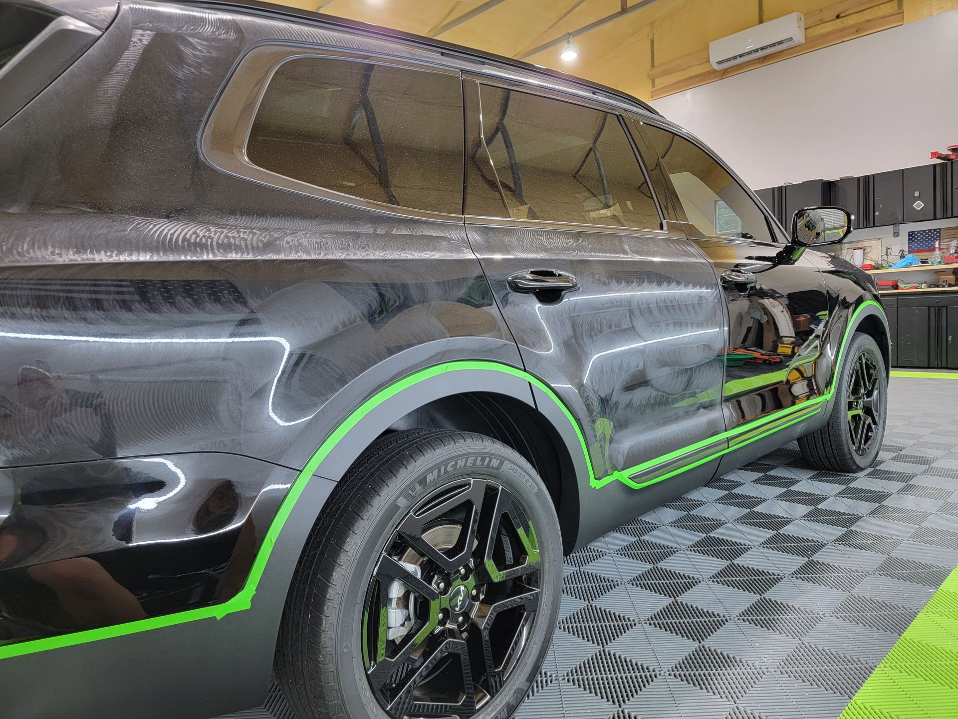 A black suv with green stripes on the side is parked in a garage.