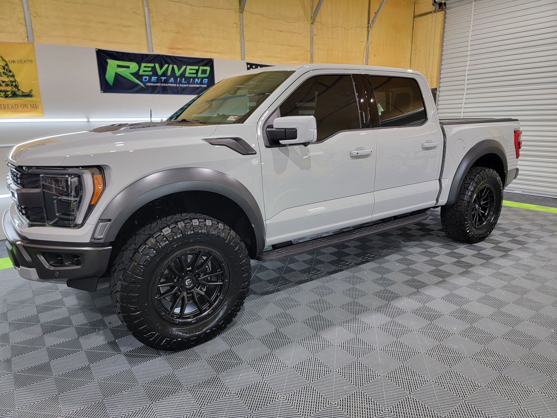 A white ford f150 raptor is parked in a showroom.