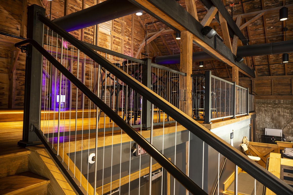 A staircase in a building with a metal railing and wooden steps. Composite deck and custom railing State College