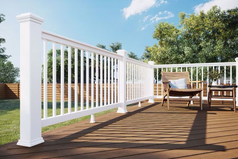 A wooden deck with a white railing and a chair on it.