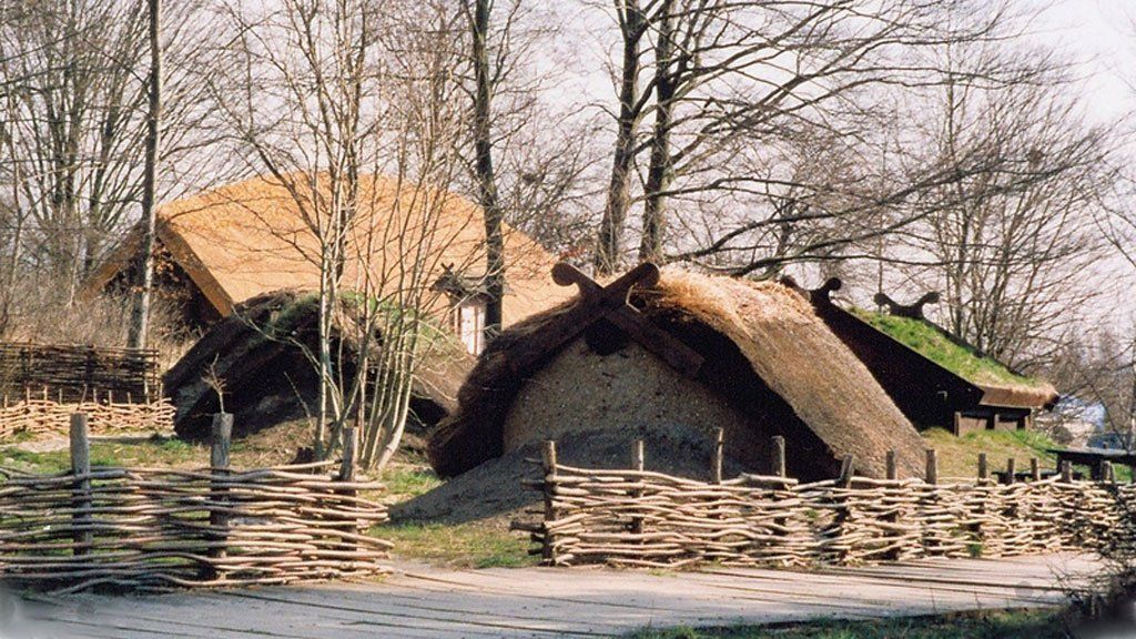 En stråtækt bygning med et plankeværk foran