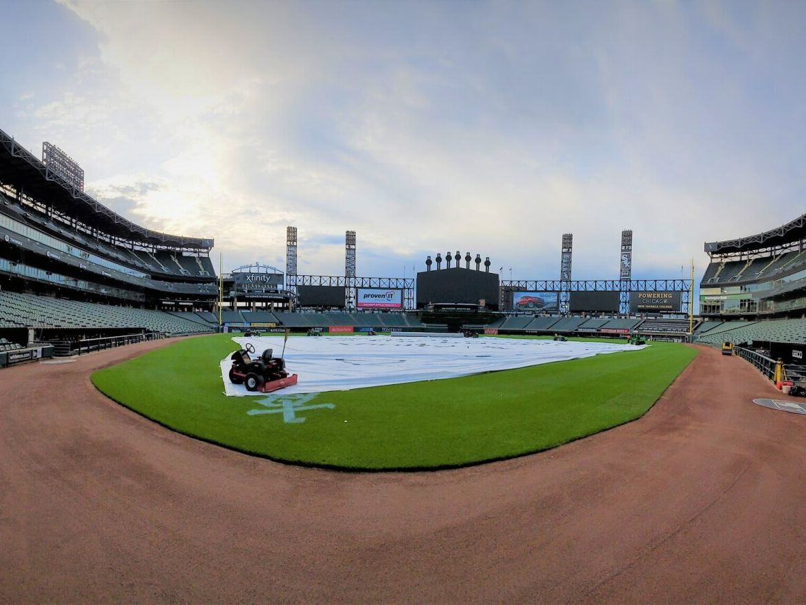 A baseball field is being covered with a tarp.