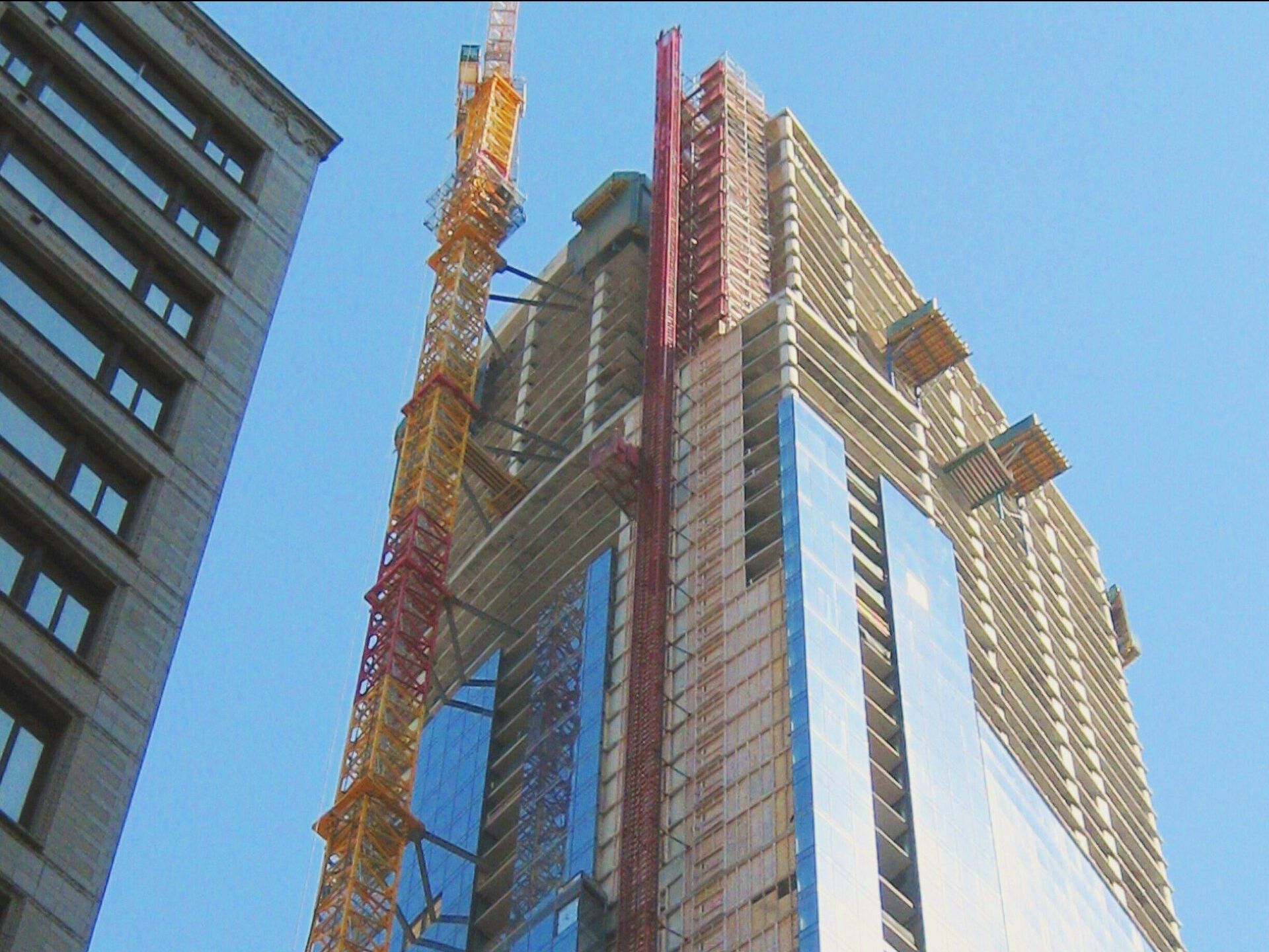 A tall building under construction with a crane in front of it