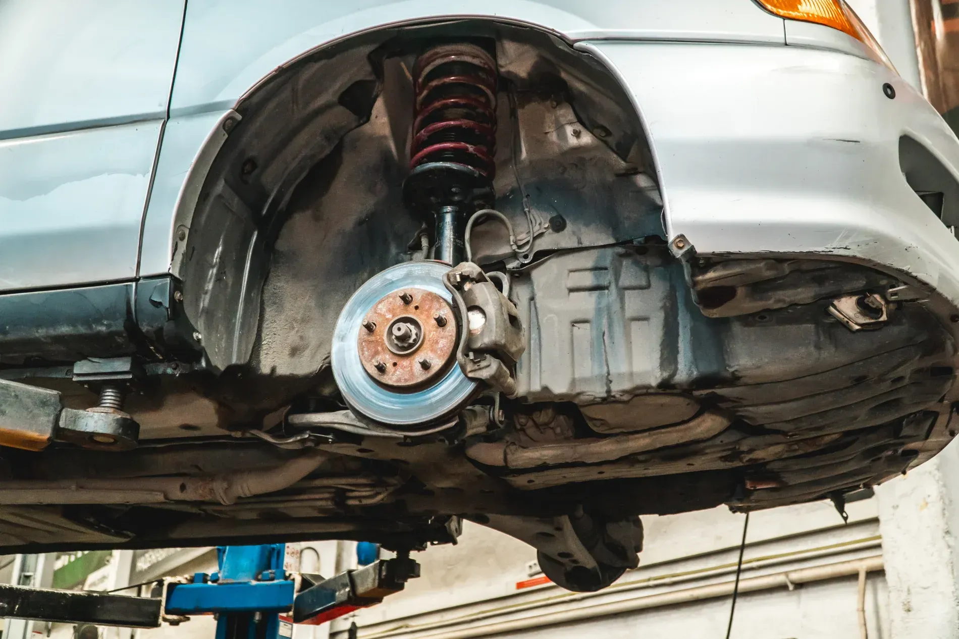 Car Wheel and Brake Assembly Exposed on a Car Lifted in a Repair Shop — Supa Auto Services In Bundaberg, North