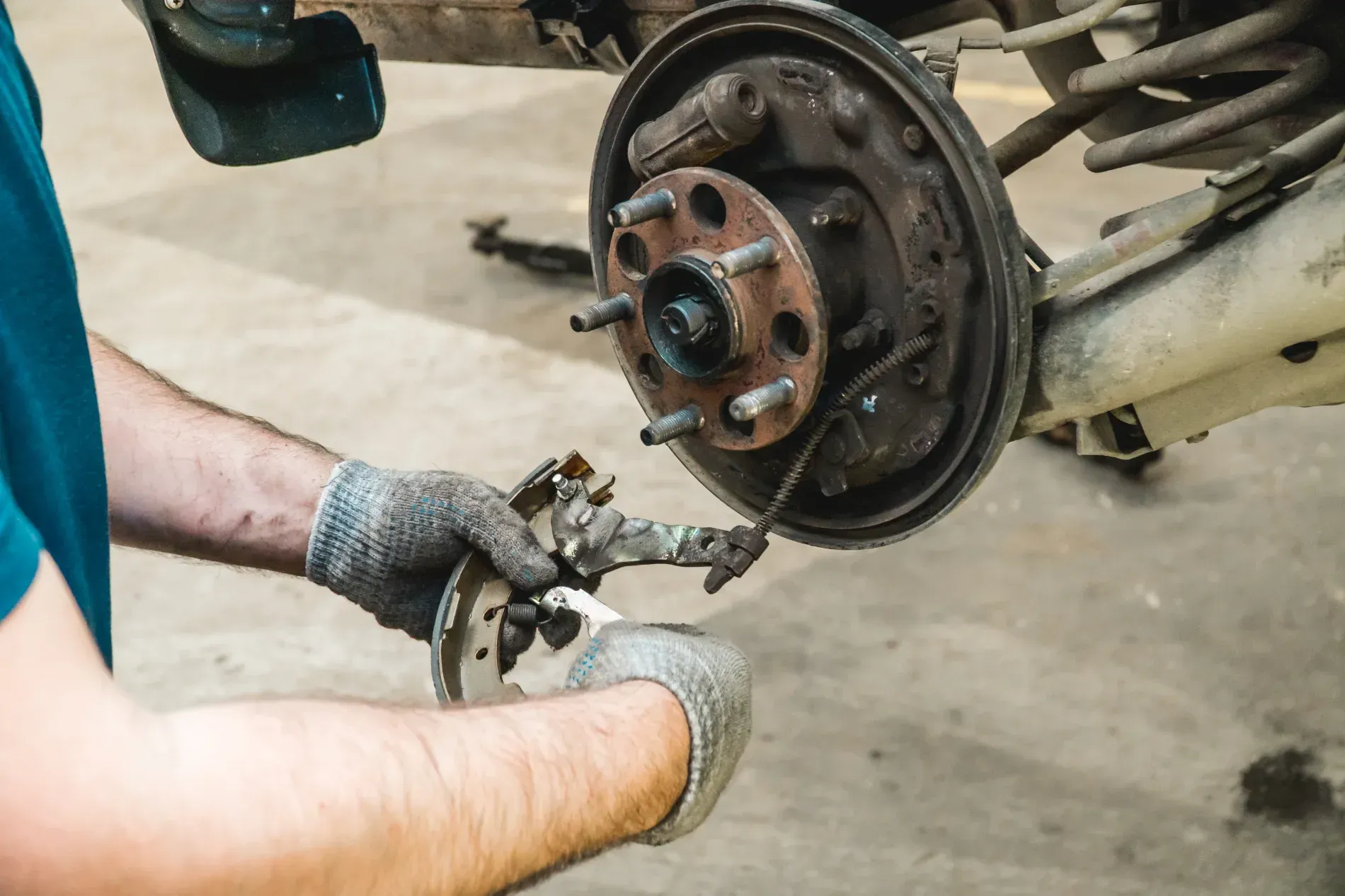 Mechanic Removing Brake Components From a Car Wheel Hub in a Garage — Supa Auto Services In Bundaberg, North