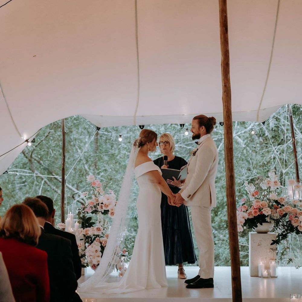 A Bride and Groom Are Holding Hands During Their Wedding Ceremony — Seed + Salt Photography In Foster, NSW