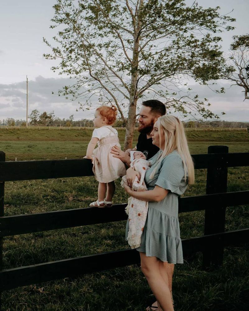 A Family Is Standing Next to A Fence Holding a Baby — Seed + Salt Photography In Foster, NSW
