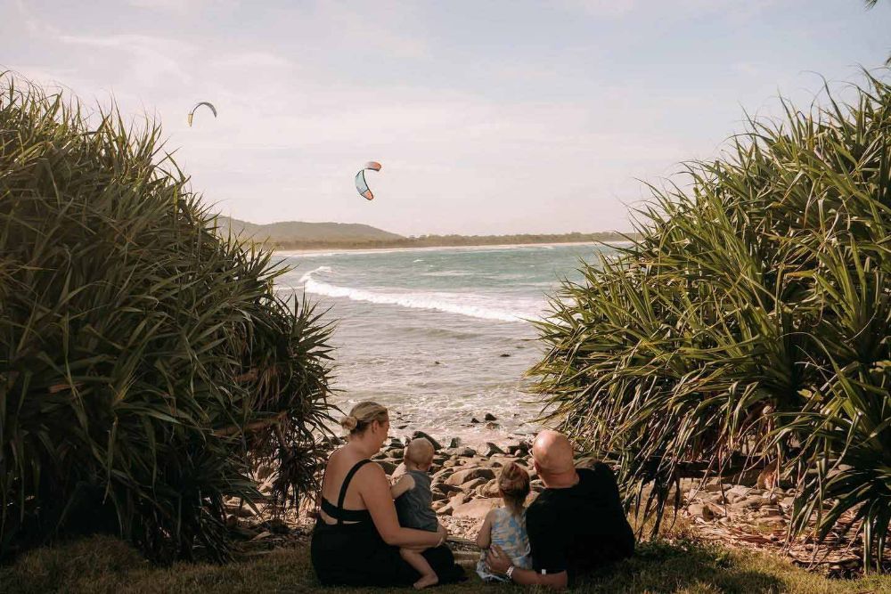 A Family Is Sitting on The Beach Looking at The Ocean — Seed + Salt Photography In Crescent Head, NSW