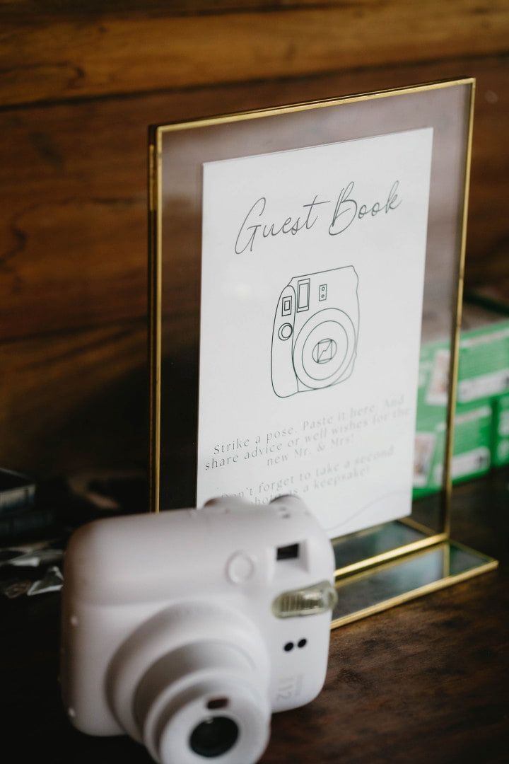 White Instant Camera on a Wooden Table Beside a Framed Sign โ Seed + Salt Photography In Smithtown, NSW