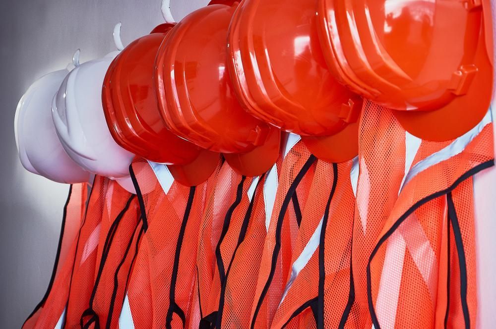 A Row of Red and White Hard Hats Hanging on A Rack — Gillespie Plumbing in Grafton, NSW