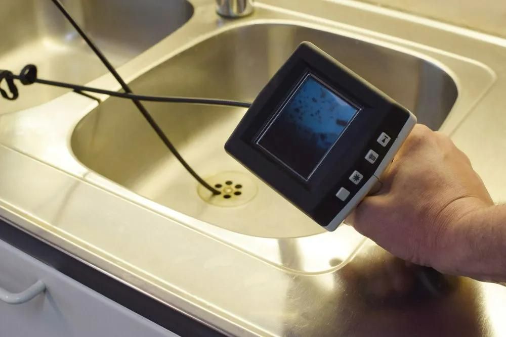 A Person Is Holding a Camera Over a Sink — Gillespie Plumbing in Grafton, NSW