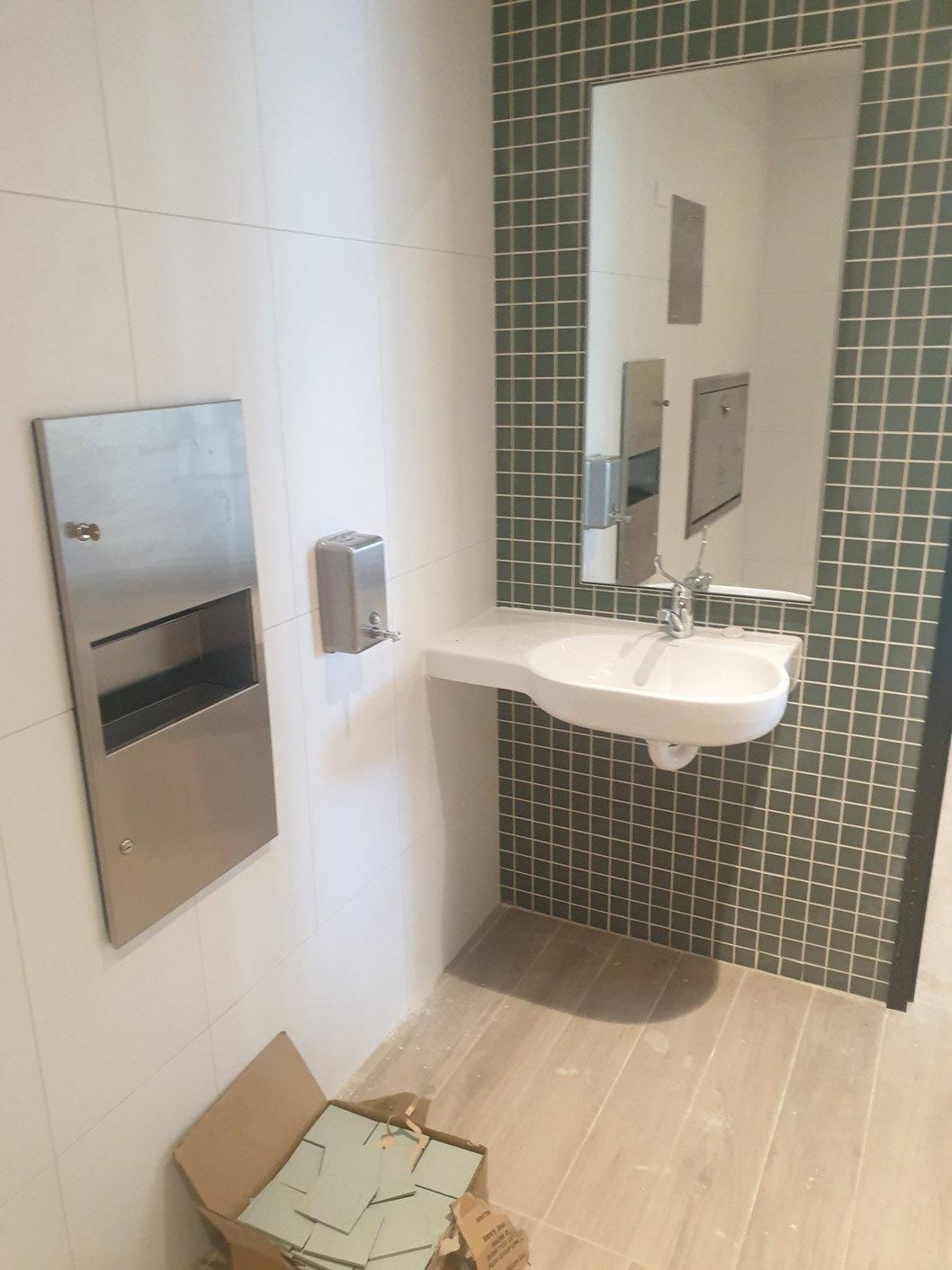 A Bathroom with A Sink, Mirror and Paper Towel Dispenser — Gillespie Plumbing in Grafton, NSW
