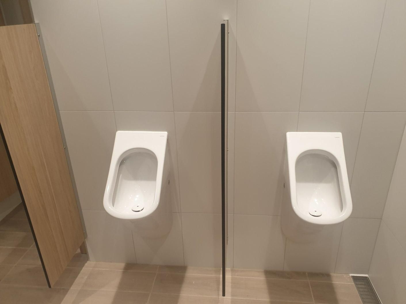 Two Urinals Are Sitting Next to Each Other in A Public Restroom — Gillespie Plumbing in Grafton, NSW