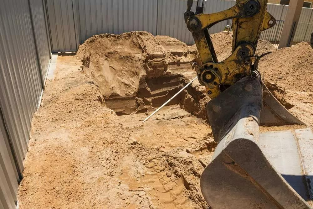 A Yellow Excavator Is Digging a Hole in The Ground — Gillespie Plumbing in Grafton, NSW