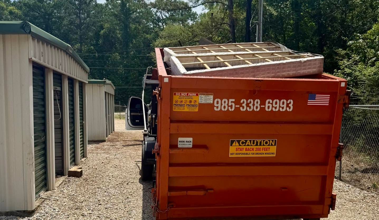 Green dumpster filled with crushed yellow and white debris in a parking lot, with the side door open