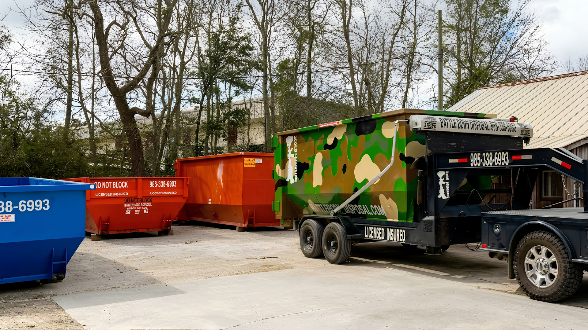 Orange dumpster bin beside a truck in a residential construction area, with houses in the background