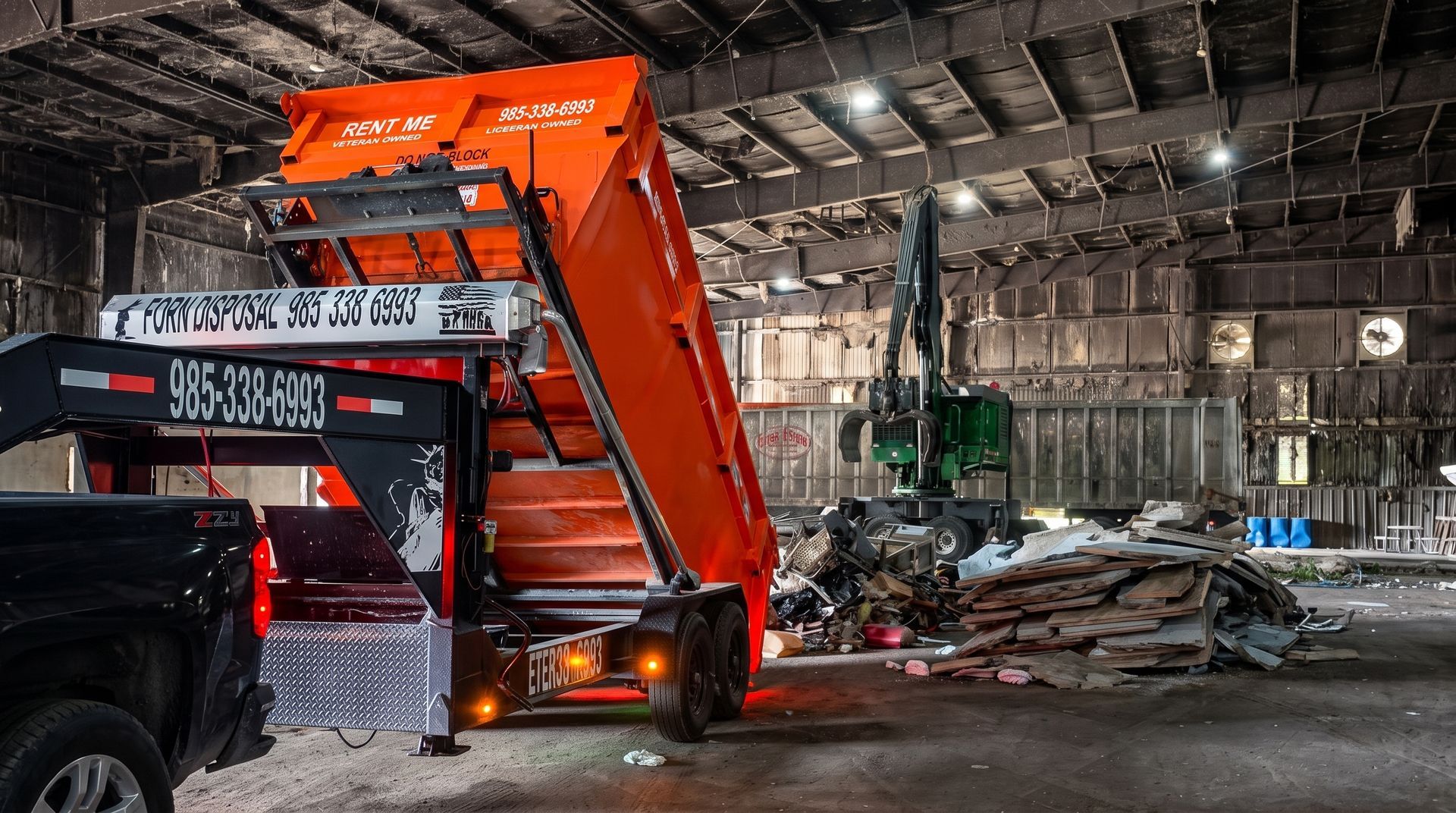 Orange excavator lifting debris inside a damaged warehouse, with piles of rubble and a truck nearby