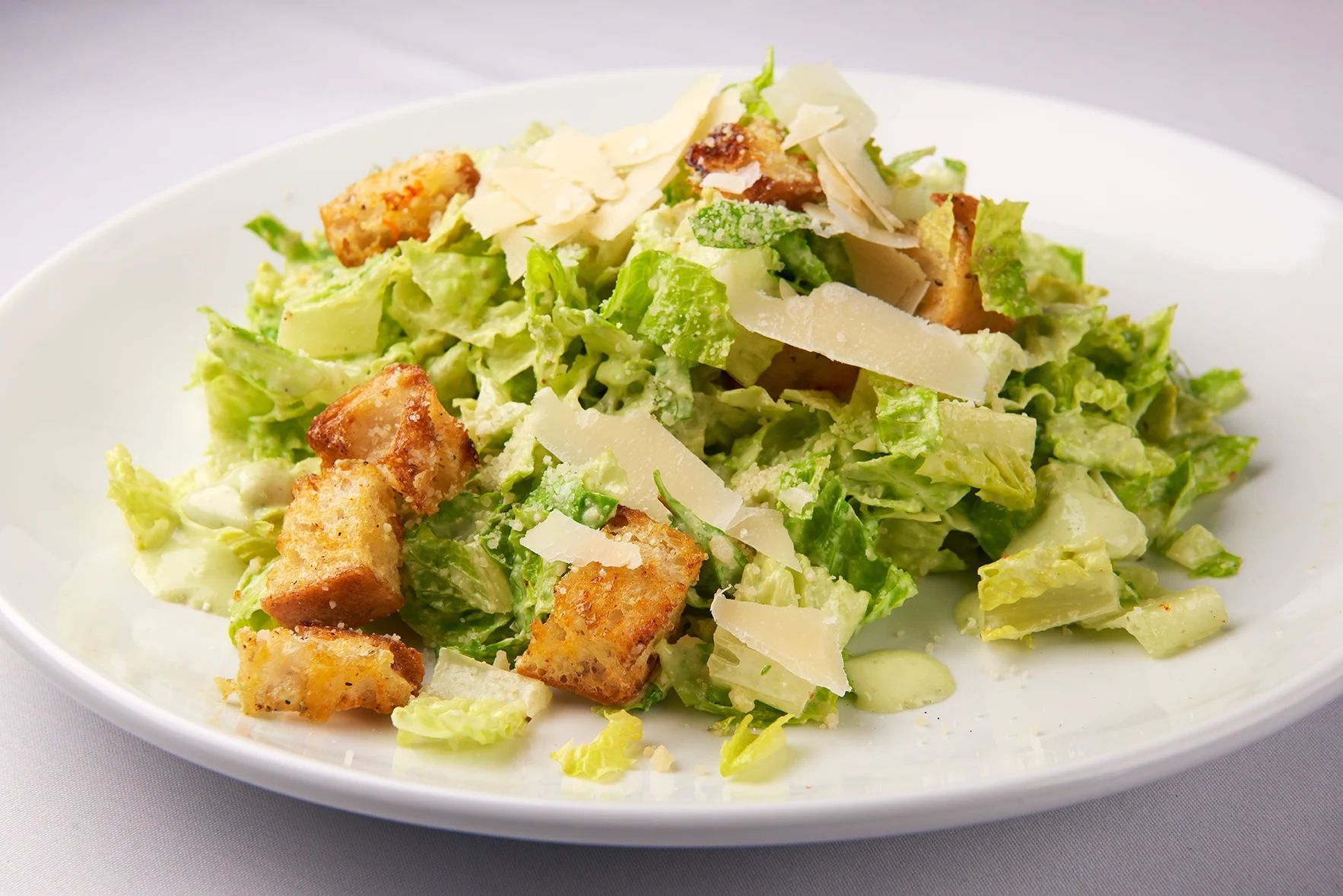 Classic Caesar A close up of a salad on a white plate on a table.