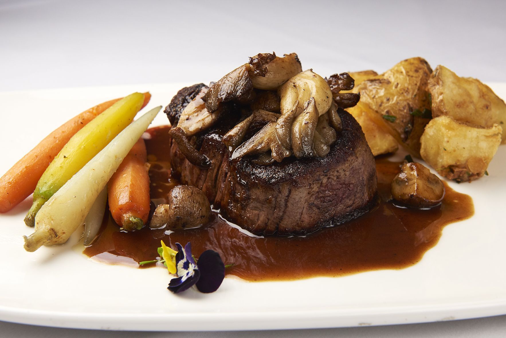 Filet Mignon Piedmontese A white plate topped with a steak and vegetables