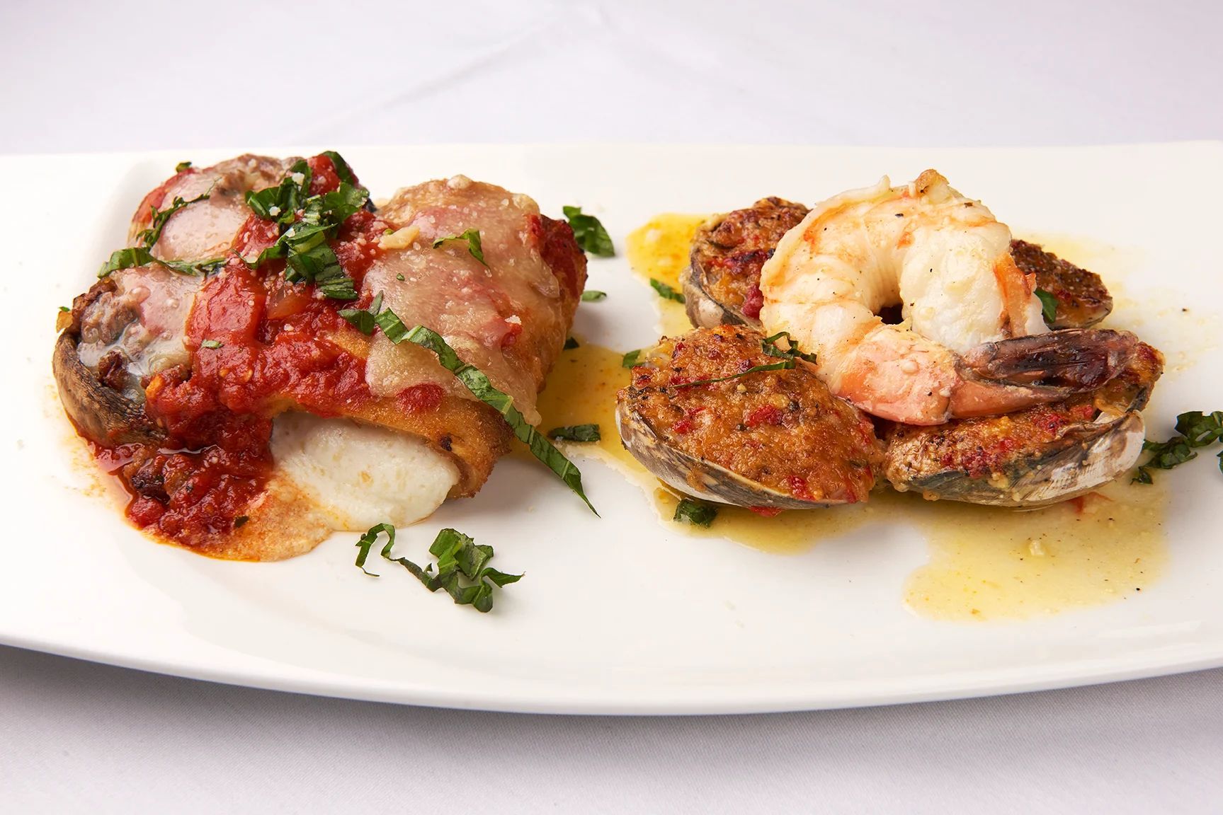 Hot Antipasto A white plate topped with two pieces of meat and shrimp