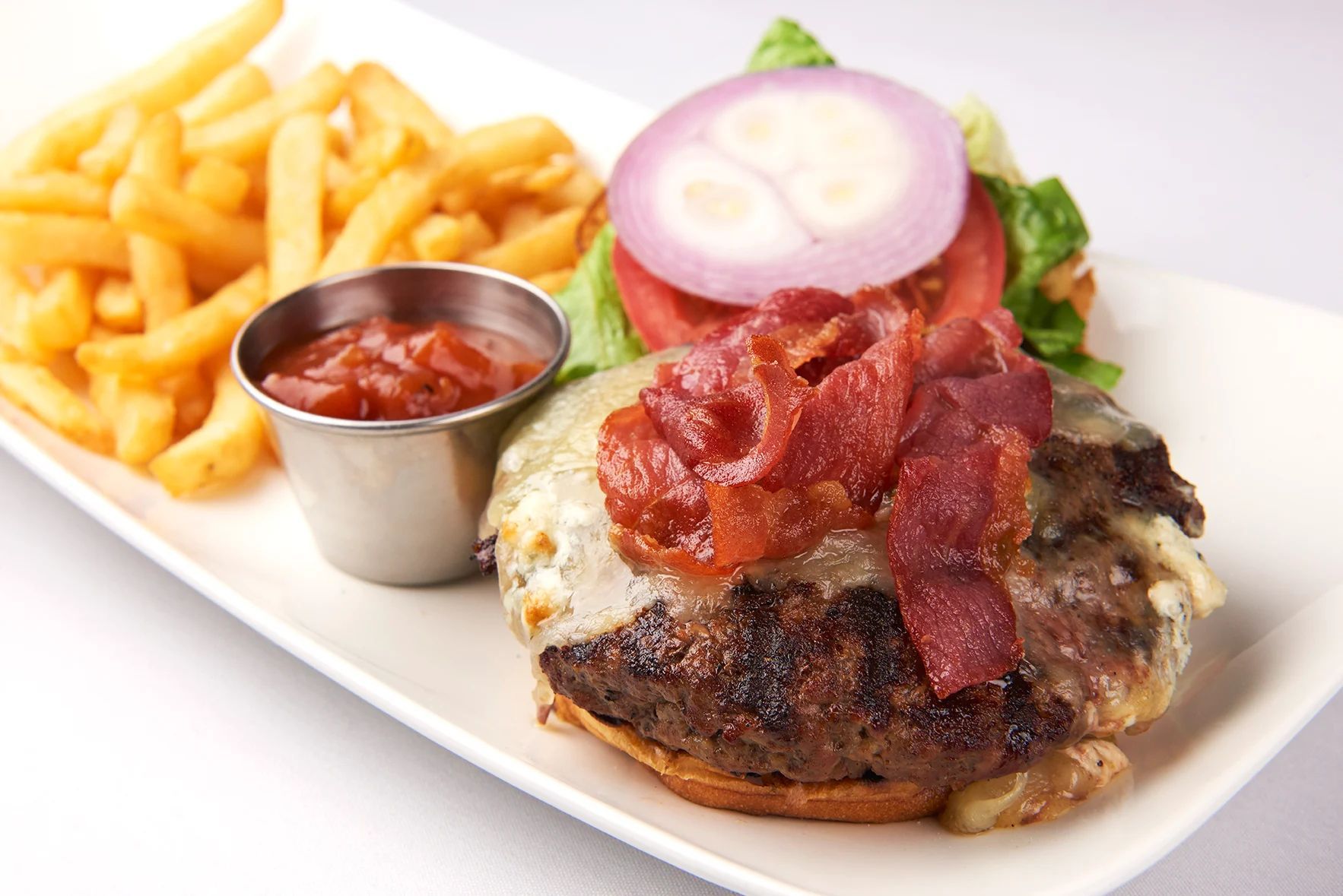 Kobe Beef Burger A white plate topped with a hamburger and french fries