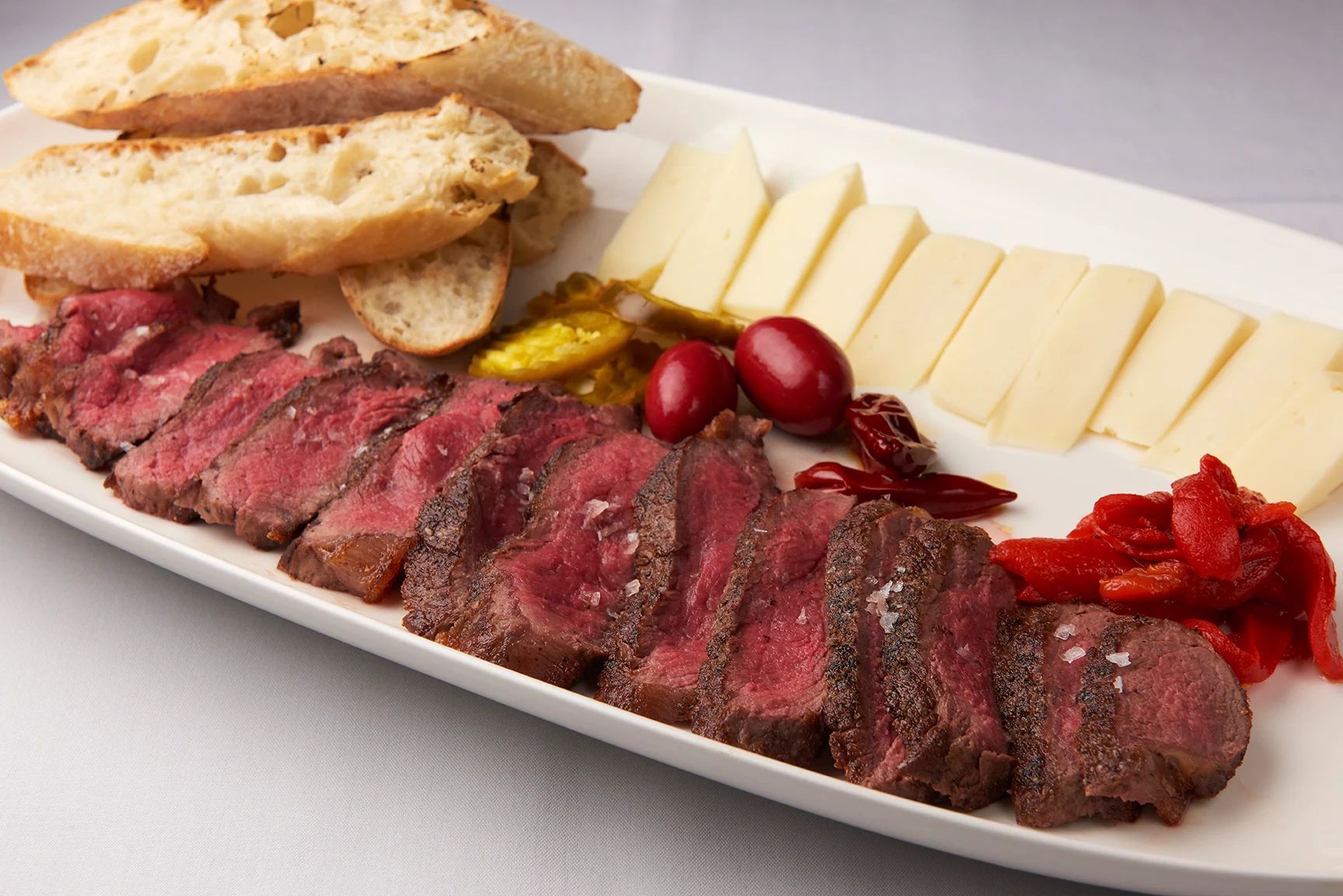 Bar Steak for Two A white plate topped with meat cheese and bread
