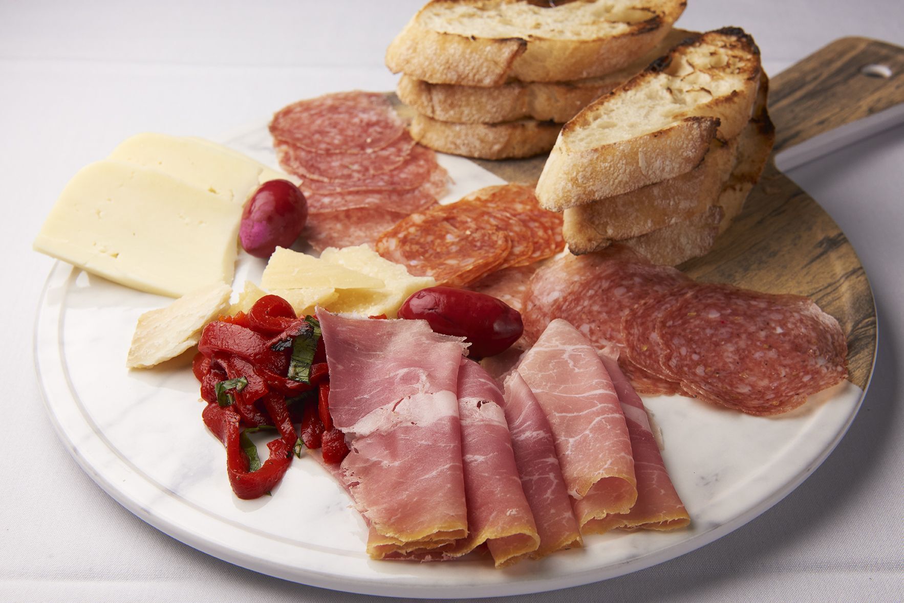 Salumi & Cheese Board A white plate topped with a variety of meats and cheeses