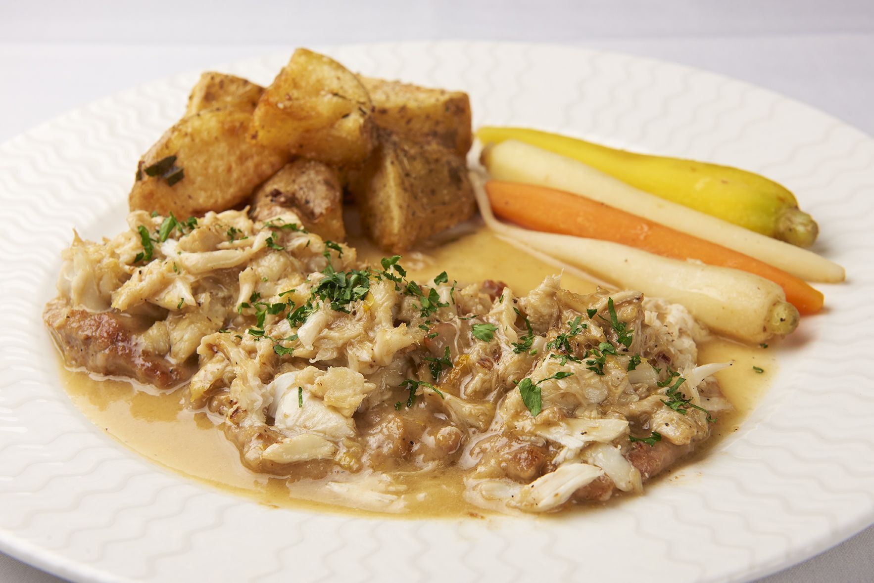 Veal Marsellaise A white plate topped with meat and vegetables on a table.
