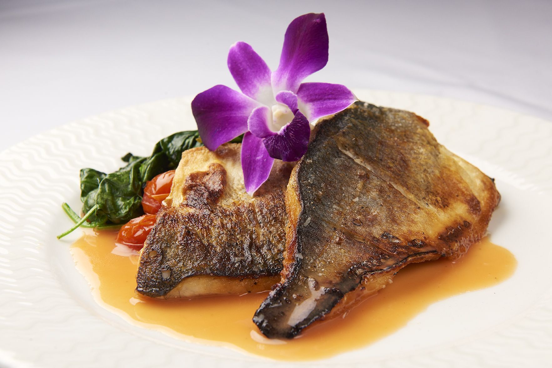 Branzino Valentina A plate of food with a purple flower on top