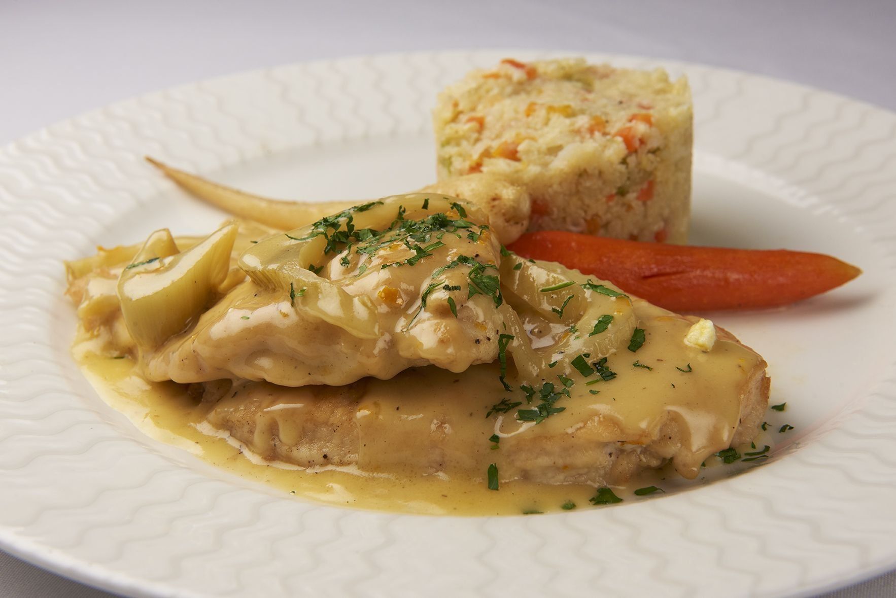 Chicken Orange Inn A white plate topped with chicken , carrots and rice.
