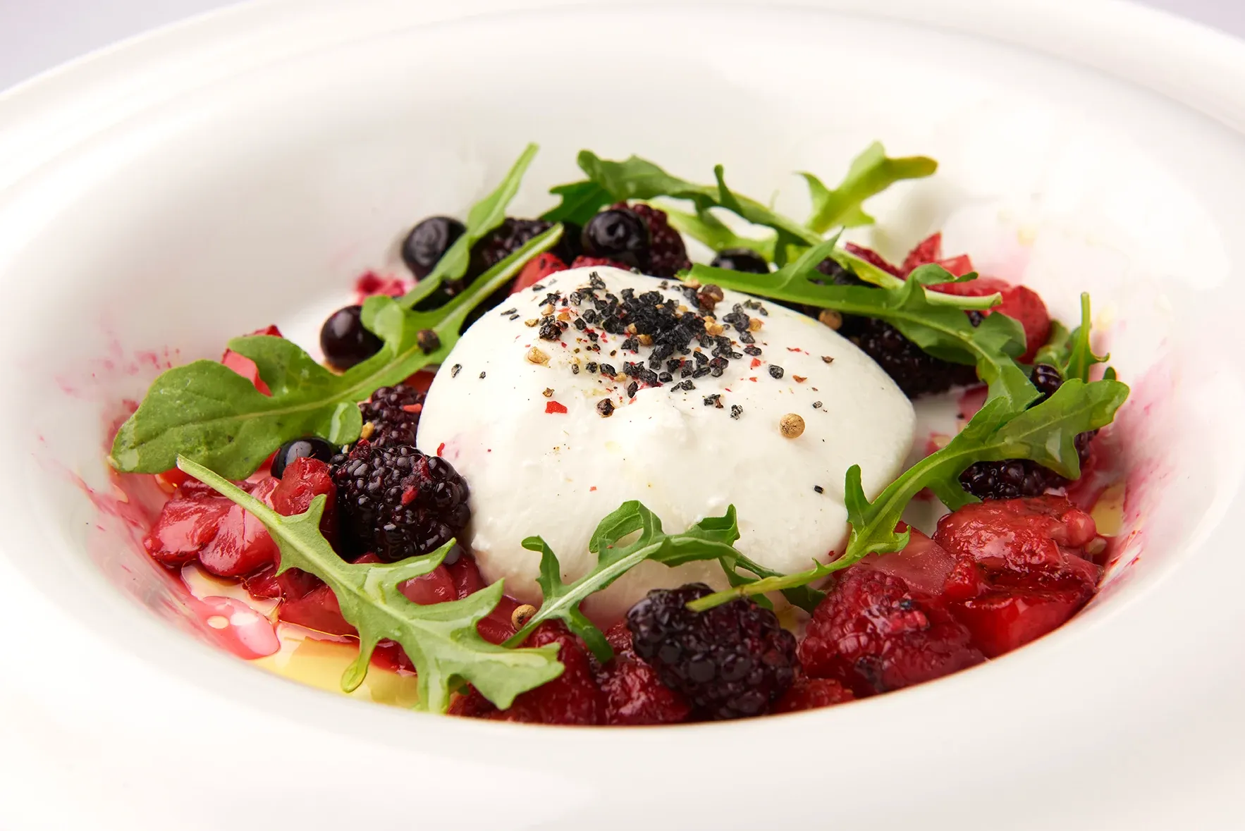 Burrata, Fresh Berry Balsamic Compote A white plate topped with a salad of berries and yogurt.