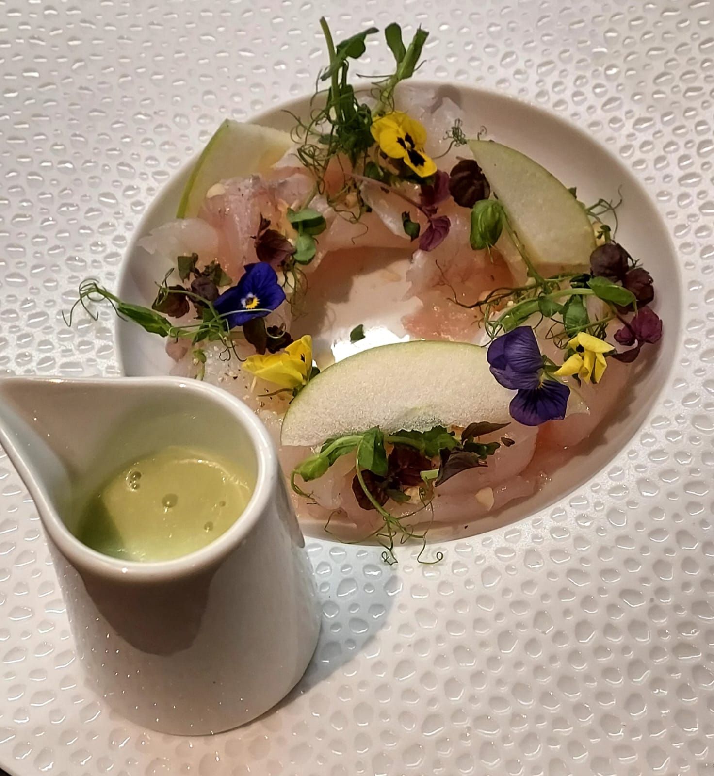 Un piatto di cibo accanto a una piccola brocca di salsa verde