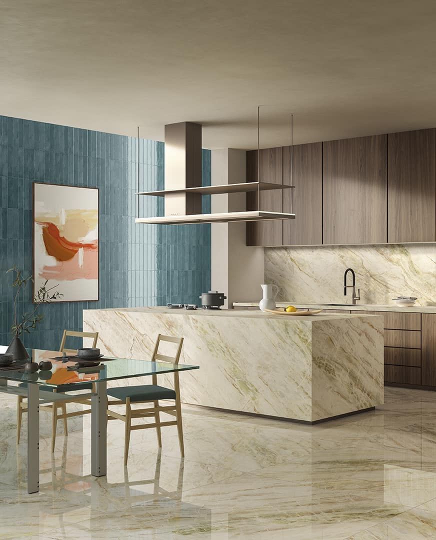 Cucina moderna con isola in marmo, mobili in legno e tavolo da pranzo in vetro. Parete con dettagli blu.