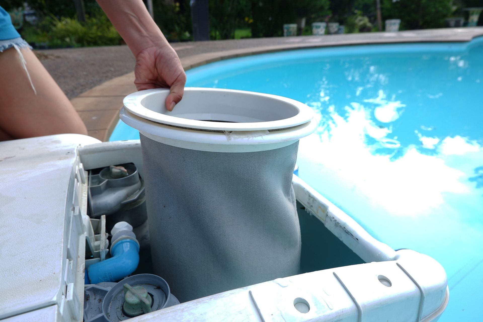 Person removing a filter bag from a pool skimmer.