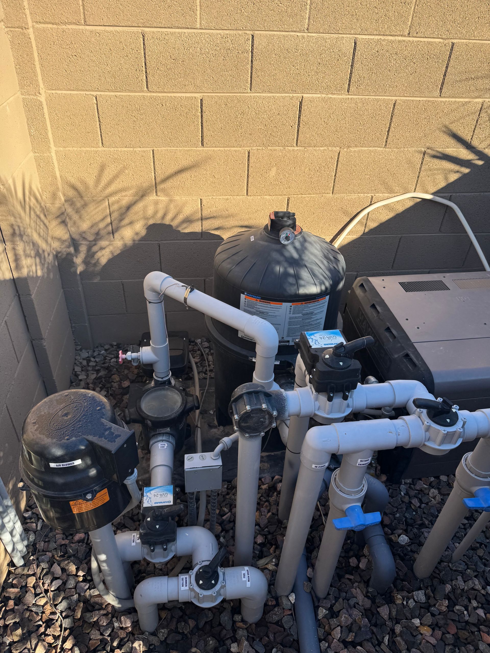 Man in red shirt and cap fixing pool decking. He uses a drill near a tool kit.