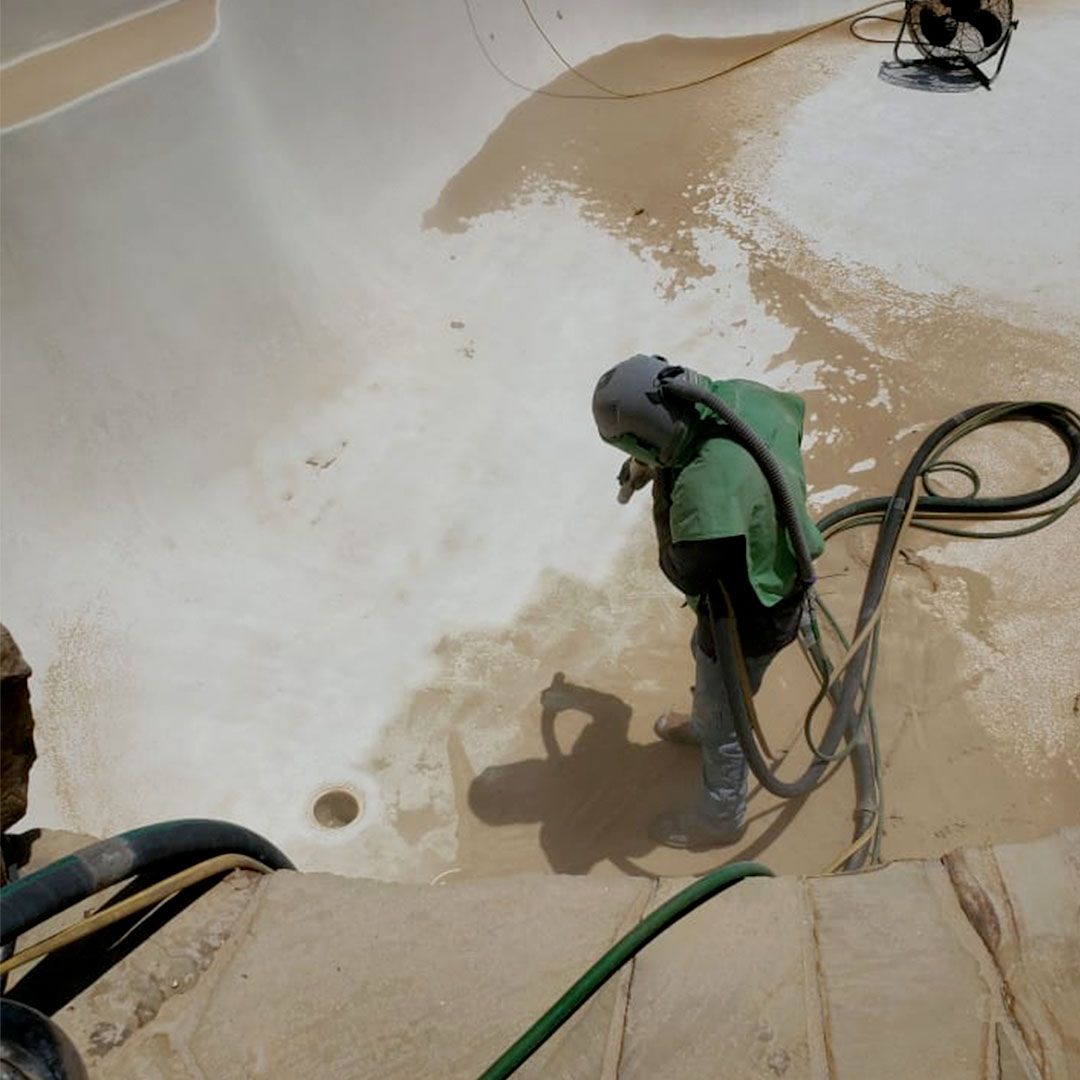 A person is cleaning a tile wall with a high pressure washer.