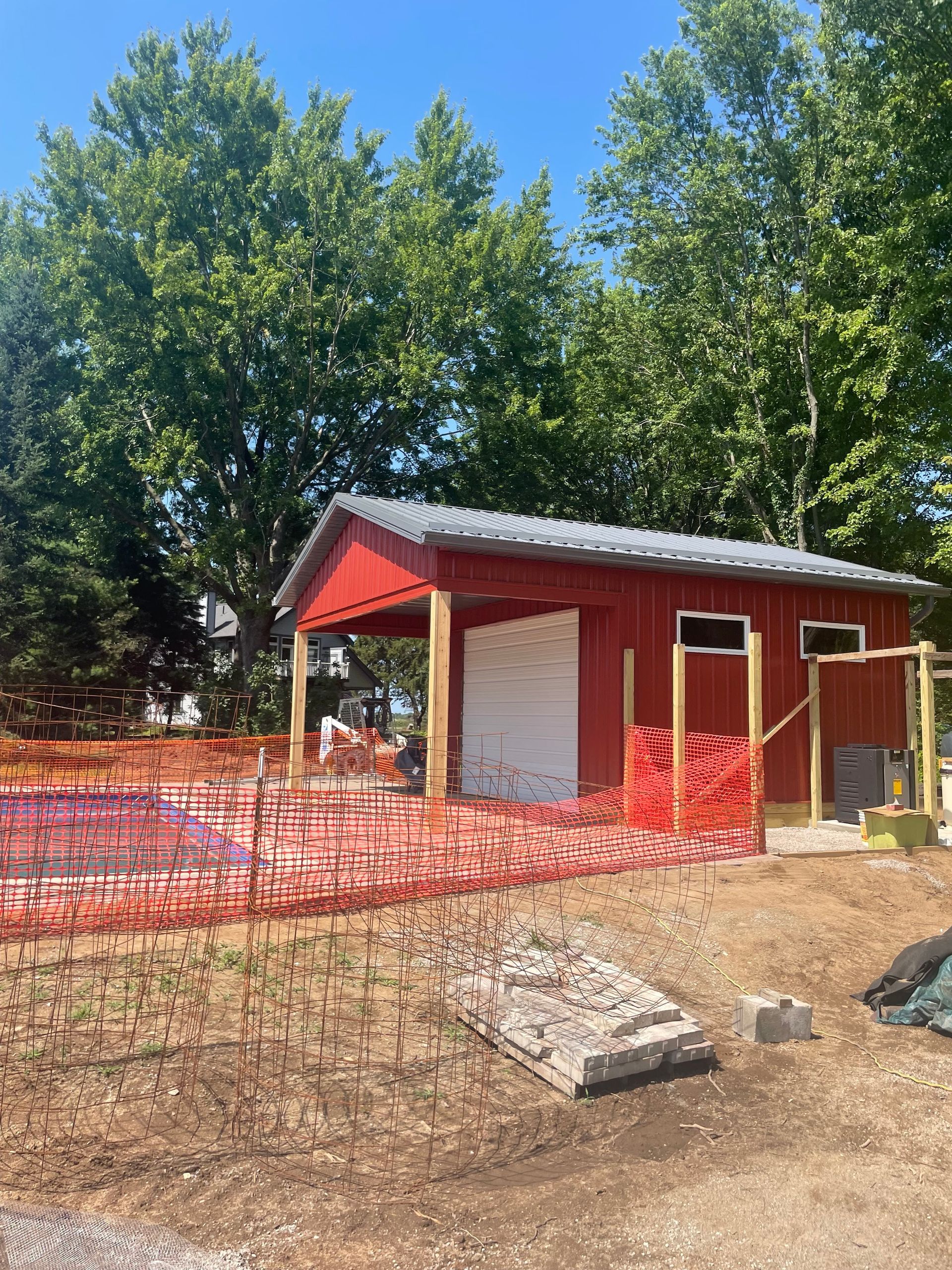 Red shed under construction, with orange safety fencing in the foreground.