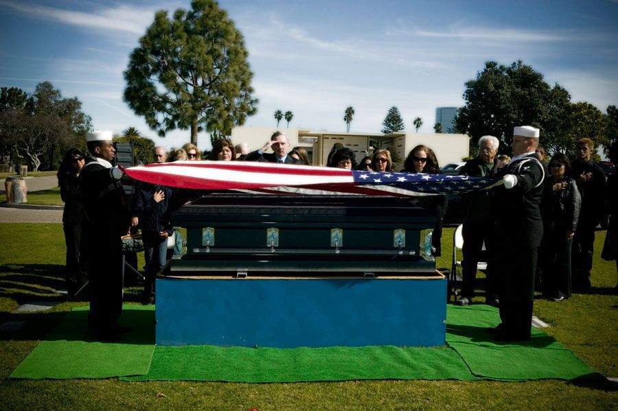 A man in a military uniform is holding an american flag in his hands.