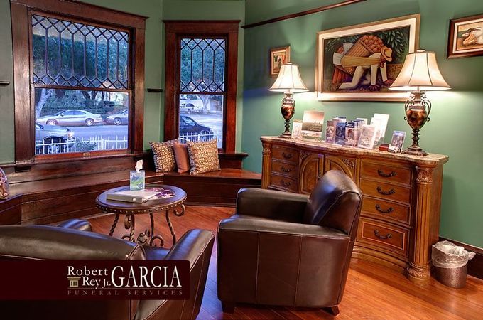 Cozy living room with leather chairs, wooden sideboard, stained-glass windows, and warm lamps