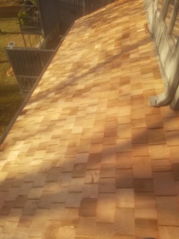 Sunlit shingled roof with a person’s legs visible at the top right
