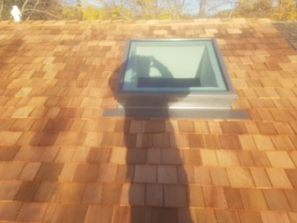 Sunlit shingled roof with a skylight and a ladder-shaped shadow