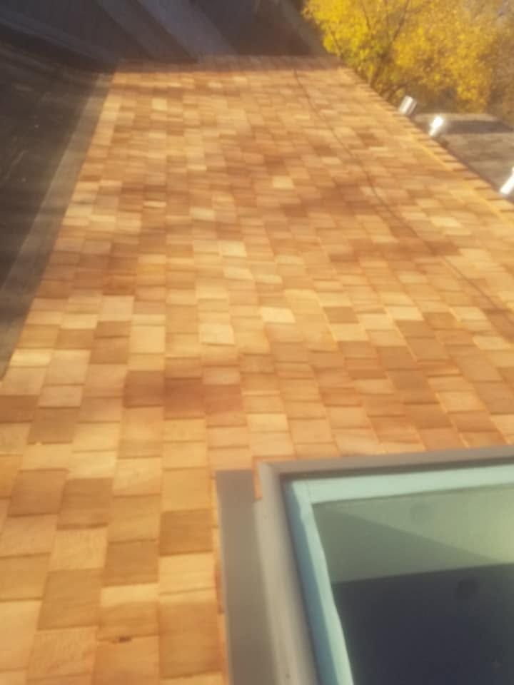 Sunlit wooden shingle roof with a skylight in the lower right corner