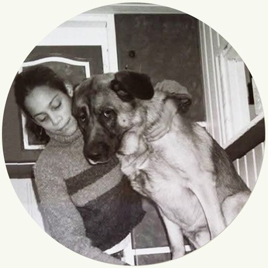 Vrouw met een hond, die elkaar liefdevol omhelst en naar beneden kijkt. Trap op de achtergrond. Zwart-wit.