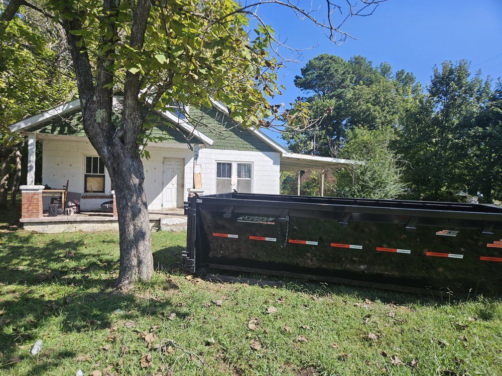 Suburban house with trees and a black utility trailer parked in the front yard