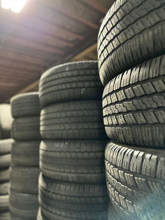 Stacks of black car tires in a warehouse, viewed from a low angle.