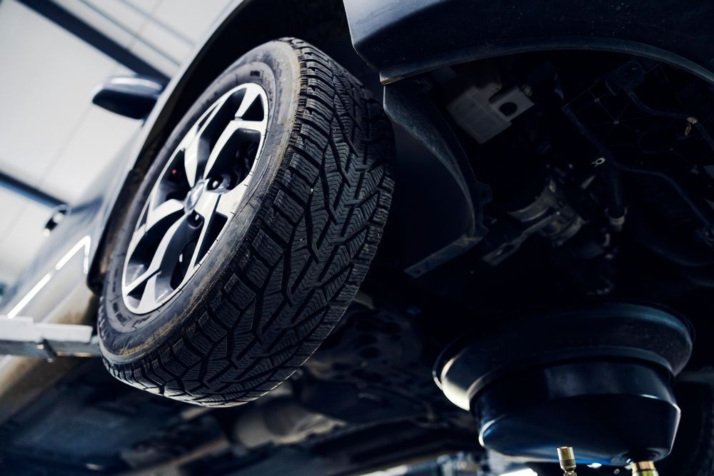 Upside-down car with wheel and suspension visible against a dark background