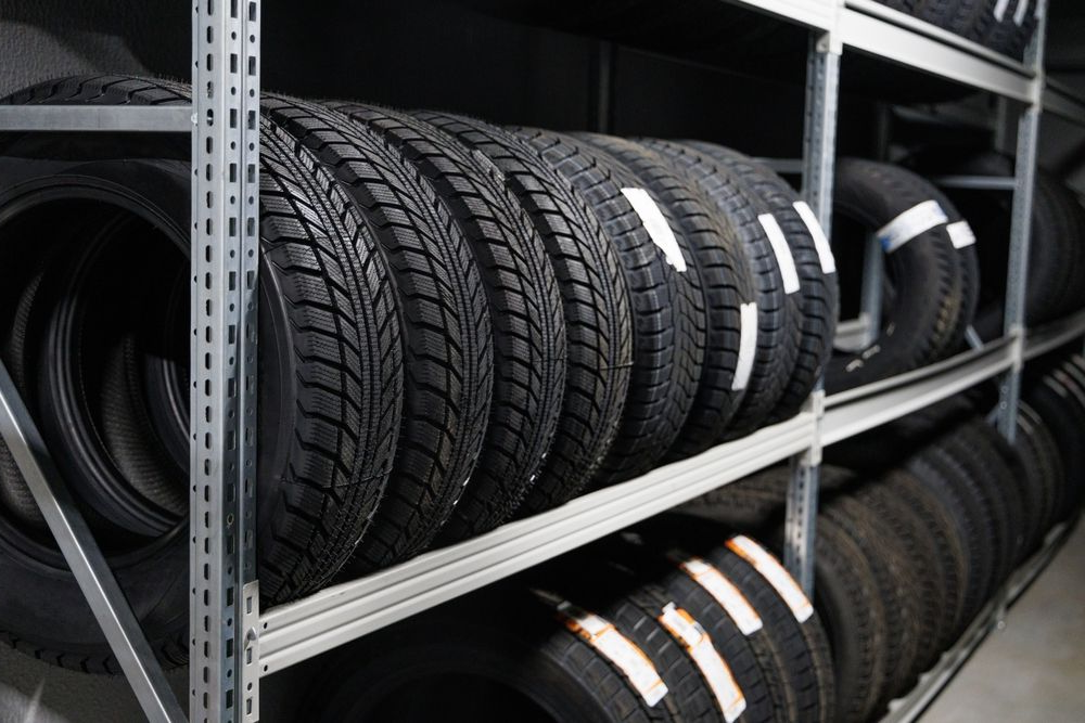 Tires stacked on metal shelves in a warehouse or auto shop.
